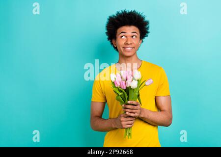 Portrait de la personne douée d'esprit tenir des tulipes fraîches fleurs regard vide espace isolé sur fond de couleur sarcelle Banque D'Images