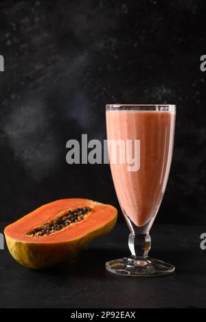 Lassi asiatique de papaye sur fond noir. Boisson fraîche froide de yaourt, eau, épices, fruits et glace. Boisson populaire en Inde et au Sri lanka. Ver Banque D'Images