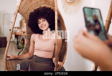 Femme noire, sourire et chaise de balançoire avec un téléphone pour une photographie pour les médias sociaux, blog ou marketing en ligne ou la publicité. Le visage de l'influenceur est heureux Banque D'Images