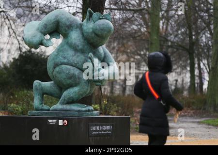 (230310) -- BRUXELLES, 10 mars 2023 (Xinhua) -- Une femme passe par une sculpture du Chat au Parc de Bruxelles à Bruxelles, Belgique, 10 mars 2023. Au total, 22 sculptures du Chat, icône de bande dessinée créée par le caricaturiste belge Philippe Gelack, sont exposées au parc de Bruxelles. L'exposition durera jusqu'à 30 juin. (Xinhua/Zheng Huansong) Banque D'Images