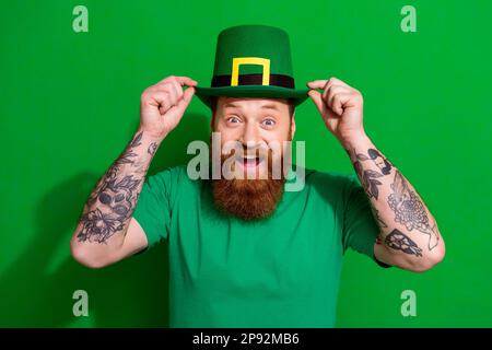 Photo d'excitée drôle gars habillé t-shirt bras casquette célébrant le jour du trèfle isolé couleur vert fond Banque D'Images