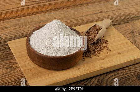 Pile de farine de sarrasin dans un bol en bois, poudre de blé buck sec, farine de sarrasin sans gluten sur fond rustique en bois vue latérale Banque D'Images