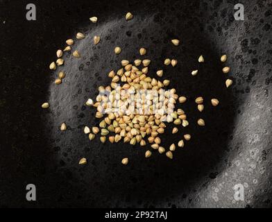 Graines de sarrasin vert cru sur plaque noire isolée, grains de blé buck sec, Cacha russe Heap, sarrasin vert non cuit vue de dessus Banque D'Images