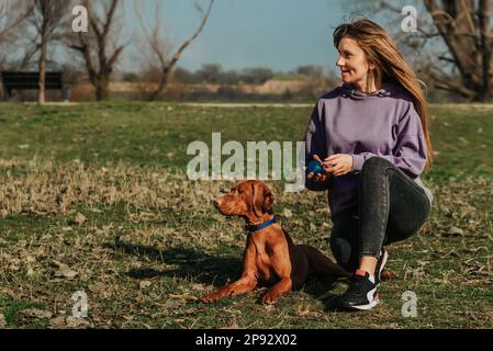 Femme et chien assis au sol à Park Banque D'Images