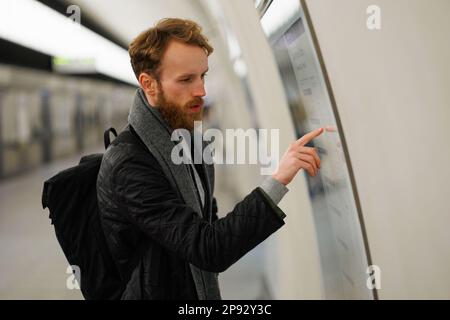 Un homme barbu regarde une carte du métro Banque D'Images