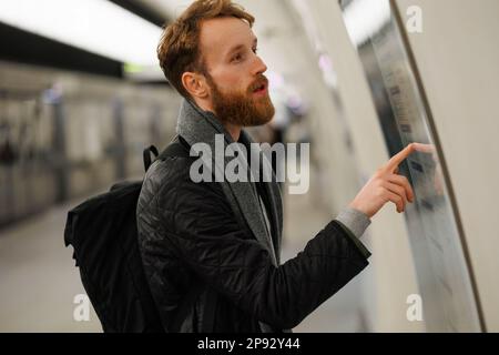 Un homme barbu regarde une carte du métro Banque D'Images