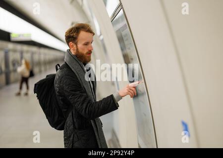 Un homme barbu regarde une carte du métro Banque D'Images