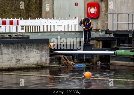 10 mars 2023, Bavière, Wörth an der Donau: Un homme enlève le flotsam de l'écluse de Geisling, où un cargo d'environ 80 mètres de long et chargé de minerai de fer avait déjà coulé dans le Danube. Selon les premiers rapports, deux personnes à bord n'ont pas été blessées, mais ont été emmenées à l'hôpital par mesure de précaution. La cause du naufrage du navire n'était pas claire au départ. Photo: Armin Weigel/dpa Banque D'Images