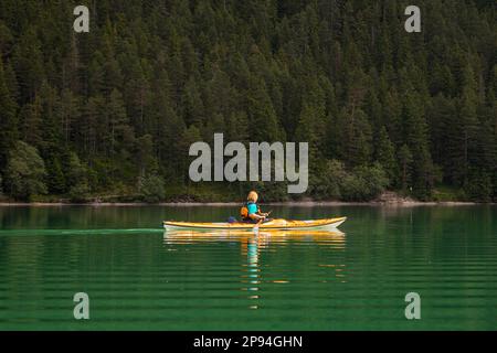 Kayak de mer (60 ans) sur le lac Heiterwanger. Banque D'Images