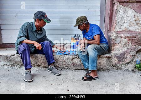 LA HAVANE, CUBA - le 1 JANVIER 2020 : deux hommes non identifiés jouent un jeu de dames sur les trottoirs de la Havane qui se trouvent sur un pas de porte. Banque D'Images