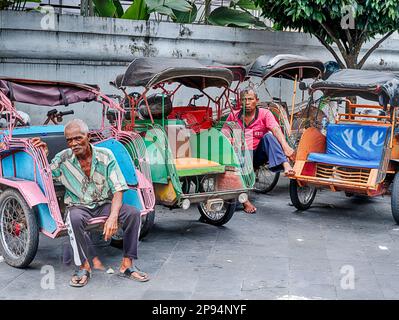 YOGYAKARTA, INDONÉSIE - le 23 JUILLET 2022 : deux pilotes de tuk tuk anonymes attendent des tours dans une rue de Yogyakarta, Indonésie. Banque D'Images