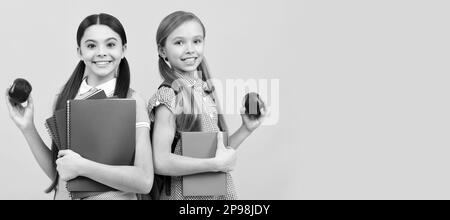 Filles d'école amis. Les élèves heureux avec des livres contiennent des pommes bio vitamine fond jaune, petit déjeuner à l'école. Bannière de l'école fille étudiante. Schoolgi Banque D'Images