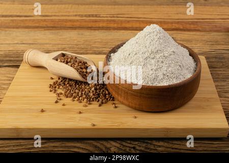 Pile de farine de sarrasin dans un bol en bois, poudre de blé buck sec, farine de sarrasin sans gluten sur fond rustique en bois vue latérale Banque D'Images