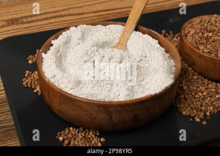 Pile de farine de sarrasin dans un bol en bois, poudre de blé buck sec, farine de sarrasin sans gluten sur fond rustique en bois Banque D'Images