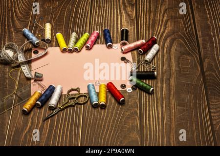 une vie de couture avec une règle en plastique, aiguilles, boutons de couleur, mètre ruban, fils assortis, des ciseaux millésimés dorés sur une table en bois marron wi Banque D'Images