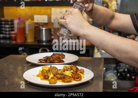 Un serveur propose une cuisine asiatique avant de la servir aux tables d'un restaurant chinois Banque D'Images