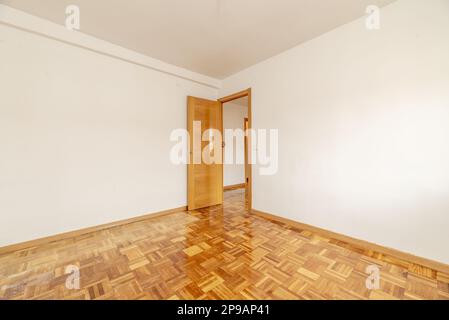 Cette chambre présente des murs peints en blanc lasio, du parquet en lamelles de chêne et une porte en cerisier Banque D'Images