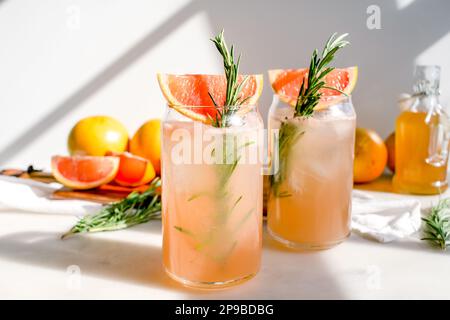 Miel romarin pamplemousse sodas garni de pamplemousse rouge : sodas sans alcool servis dans des verres en forme de boîte avec glaçons Banque D'Images