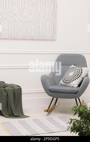 Intérieur de chambre élégant avec tapis, plante et fauteuil à bascule confortable Banque D'Images