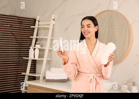 Jeune femme avec bloc menstruel et tampon dans la salle de bains Banque D'Images