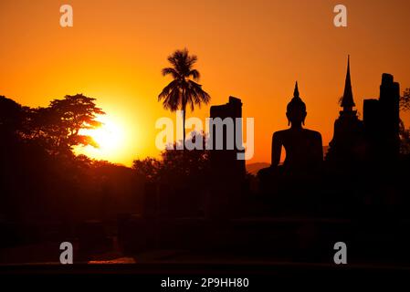 Silhouette des ruines de l'ancien temple bouddhiste Wat Chana Songkhram sur fond de coucher de soleil orange. Parc historique de Sukhotai. Thaïlande Banque D'Images