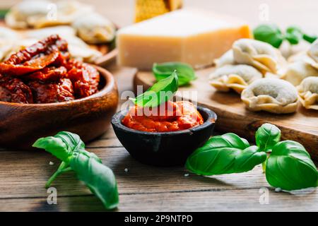 Cuisine maison - pâtes tortellini crues au pesto de tomate, tomates séchées et basilic Banque D'Images