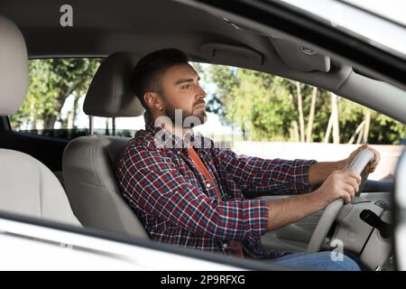 Beau jeune conducteur assis dans une voiture moderne Banque D'Images