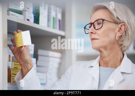 Pharmacien, pharmacie et femme lisant les effets secondaires sur l'étiquette de médicament, les pilules ou la boîte dans la pharmacie. Santé, bien-être et médecin regardant Banque D'Images