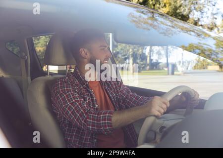 Beau jeune conducteur assis dans une voiture moderne, vue par le pare-brise Banque D'Images