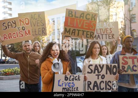 Des manifestants manifestant différents slogans anti-racisme à l'extérieur. Personnes portant des signes avec des phrases Banque D'Images