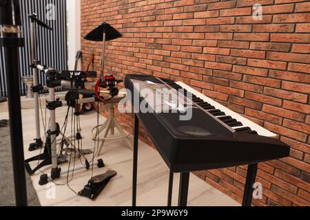 Instruments de musique près du mur de briques rouges à l'intérieur, accent sur le synthétiseur Banque D'Images