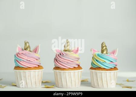 Cupcakes et confettis adorables au licorne sur une table blanche Banque D'Images