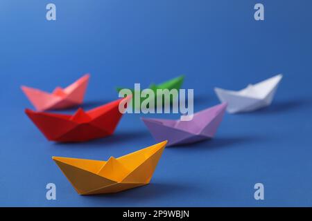 Beaucoup de bateaux en papier faits main colorés sur fond bleu. Art origami Banque D'Images