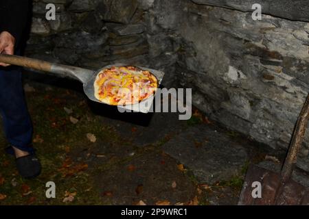 Staycation pizza traditionnelle au feu de bois cuisson dans un four en pierre Banque D'Images