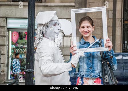 Artiste MIME artiste de rue, habillé et peint en blanc, habillé comme un artiste et tenant un cadre sur le visage du sujet comme s'il s'agit d'un portrait. Banque D'Images