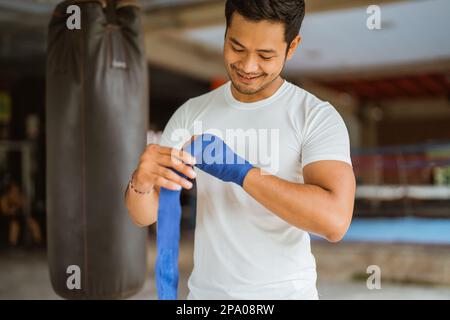un boxeur asiatique mâle portant les gants de boxe tout en se tenant debout sur le ring Banque D'Images