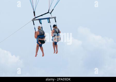 Vue arrière de deux amis en parachute ascensionnel contre le ciel bleu au Mexique Banque D'Images