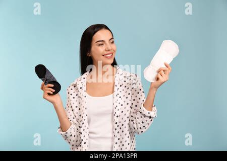 Jeune femme avec des électrodes menstruelles réutilisables et jetables sur fond bleu clair Banque D'Images