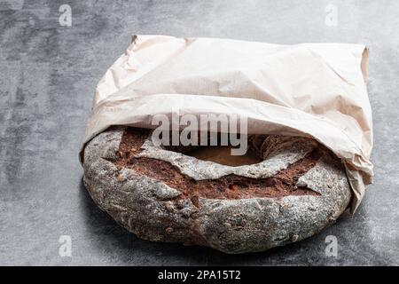 Arrondir le pain de seigle fraîchement cuit dans un sac de papier sur fond gris Banque D'Images