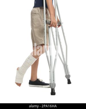 Garçon avec jambe blessée utilisant des béquilles sur fond blanc, gros plan Banque D'Images