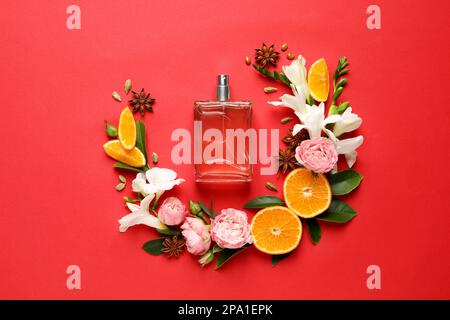 Composition de la couche plate avec bouteille de parfum et agrumes frais sur fond rouge Banque D'Images