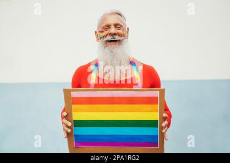 Hipster homme senior à la fierté gay tenant la bannière lgbt arc-en-ciel - Focus sur le visage Banque D'Images