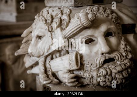 Ancien masque de théâtre, en marbre, situé à la base d'une colonne romaine à Rome - Italie Banque D'Images