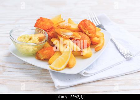 Fish and chips avec trempette et citron sur une assiette blanche Banque D'Images