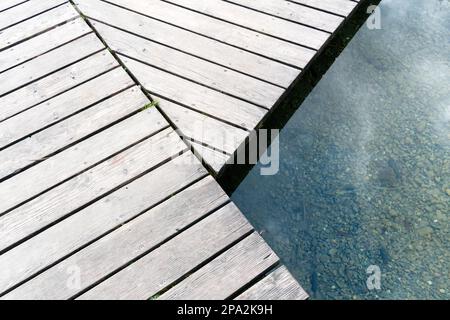 Longue et sinueuse jetée en bois sur un lac de montagne bleu foncé clair de près Banque D'Images