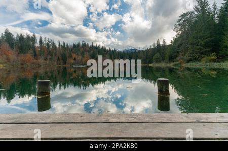 Jetée en bois et promenade avec pontons au bord d'un lac de montagne idyllique entouré d'une forêt de couleurs d'automne dans les Alpes de Suisse près Banque D'Images