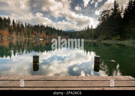 Jetée en bois et promenade avec pontons au bord d'un lac de montagne idyllique entouré d'une forêt de couleurs d'automne dans les Alpes de Suisse près Banque D'Images