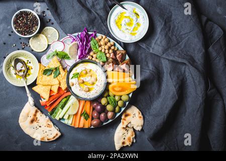 Assiette de meze avec houmous, sauce au yaourt, assortiment d'en-cas. Espace pour le texte. Houmous, bâtonnets de légumes, pois chiches, olives, pita, jetons. Plaque, centrale Banque D'Images