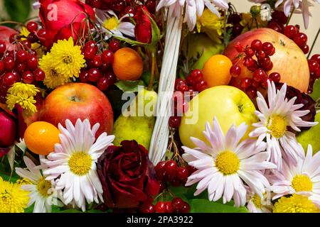 Une variété de légumes, de baies et de fleurs dans un panier. Cadeaux d'automne dans un panier en osier gros plan Banque D'Images