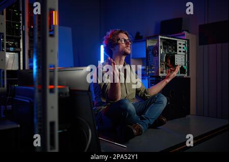 Un technicien pensif méditant dans la salle des serveurs d'un centre de données moderne Banque D'Images